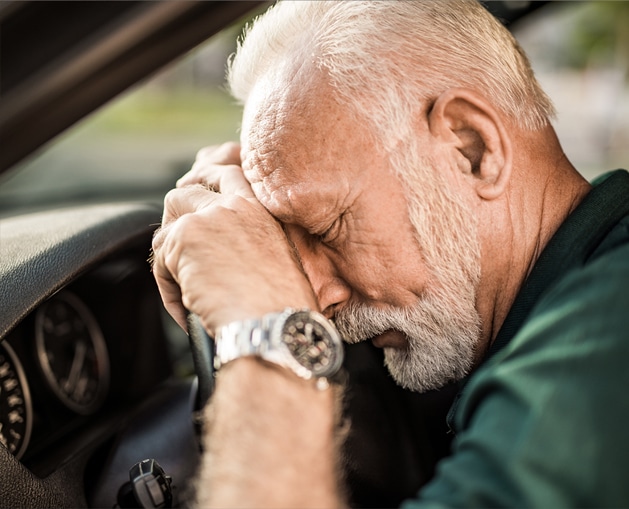 older man sleeping on the wheel of a car