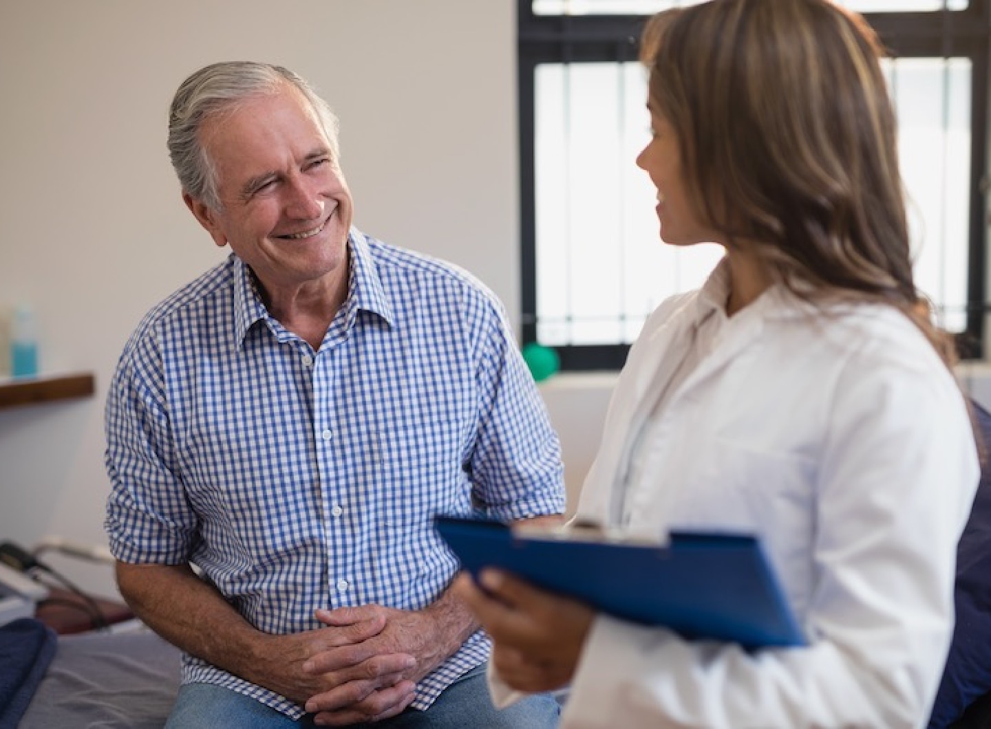 doctor looking at older male patient smiling