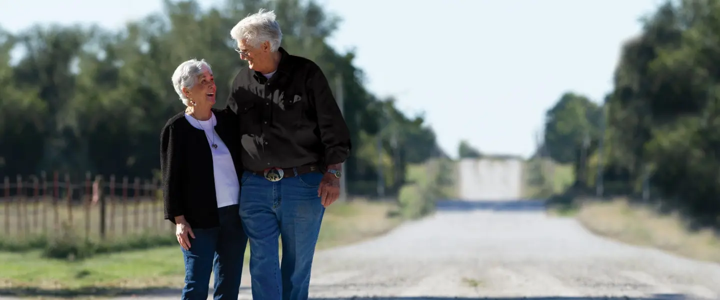 older couple looking at each other smiling down a dirt road